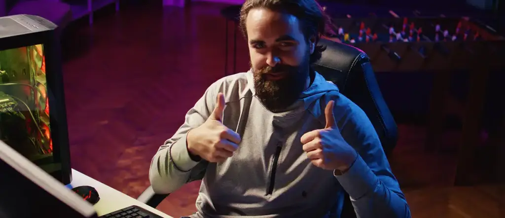 Een bebaarde man zit achter de computer en geeft les.